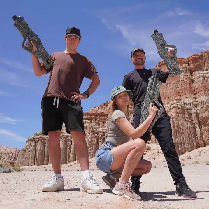 Group posing with laser tag equipment in a scenic desert location under clear skies