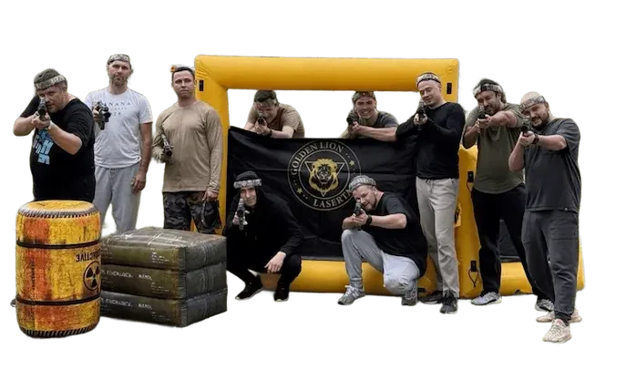Group of men posing with laser tag guns in front of a Golden Lion Lasertag inflatable barricade at an outdoor park event.