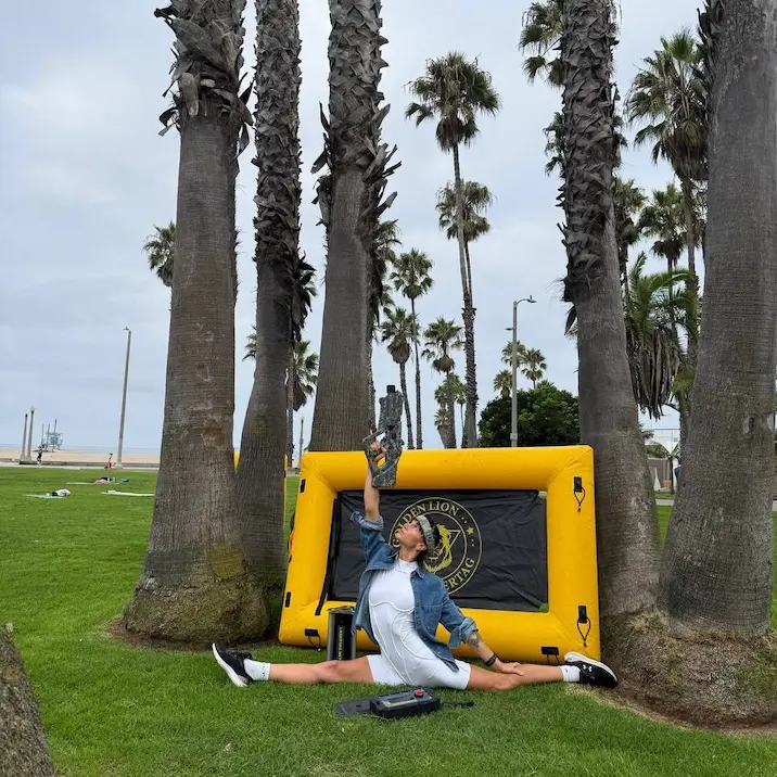 Young woman aiming with a laser tag blaster during a beachside game with inflatable covers.