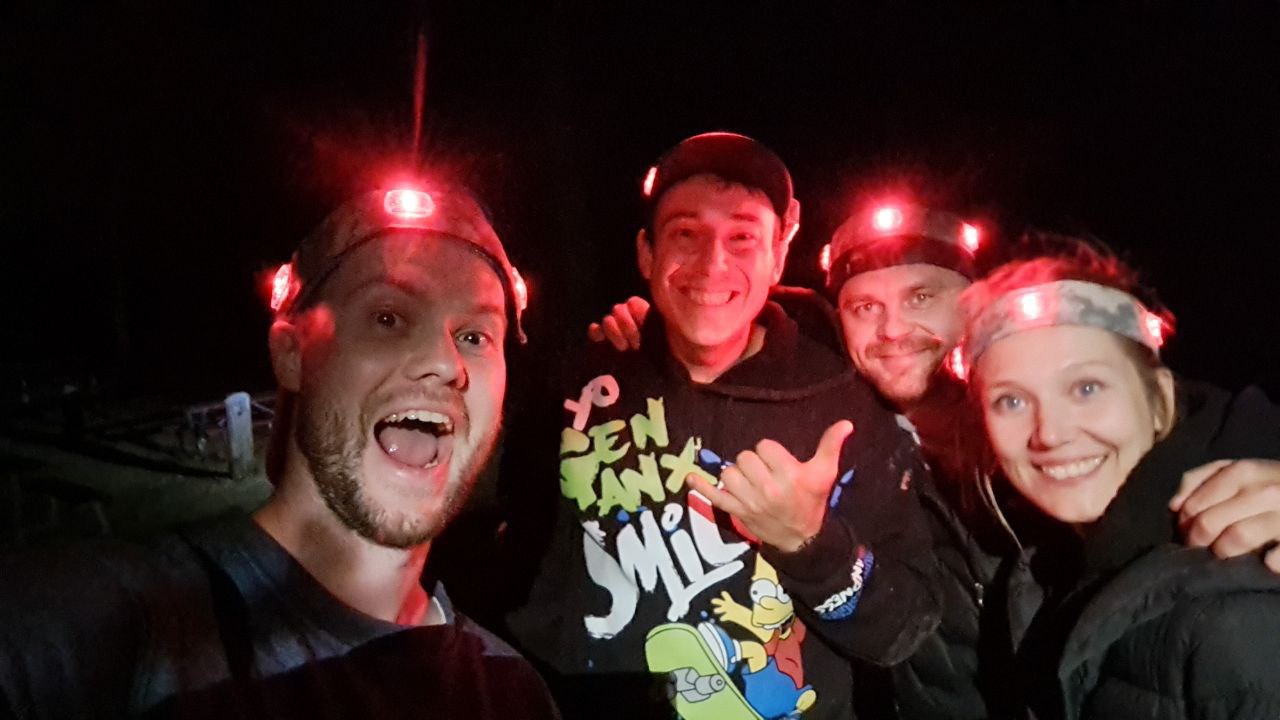 A group of friends wearing headlamps with red lights enjoying a night laser tag game in Los Angeles, smiling and posing for a fun photo.