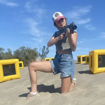 Children enjoying an outdoor laser tag game surrounded by palm trees and inflatable obstacles.